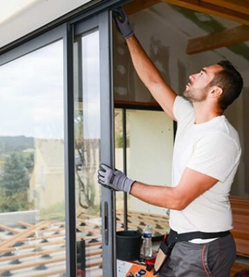 handsome young man installing bay window in a new house construction site